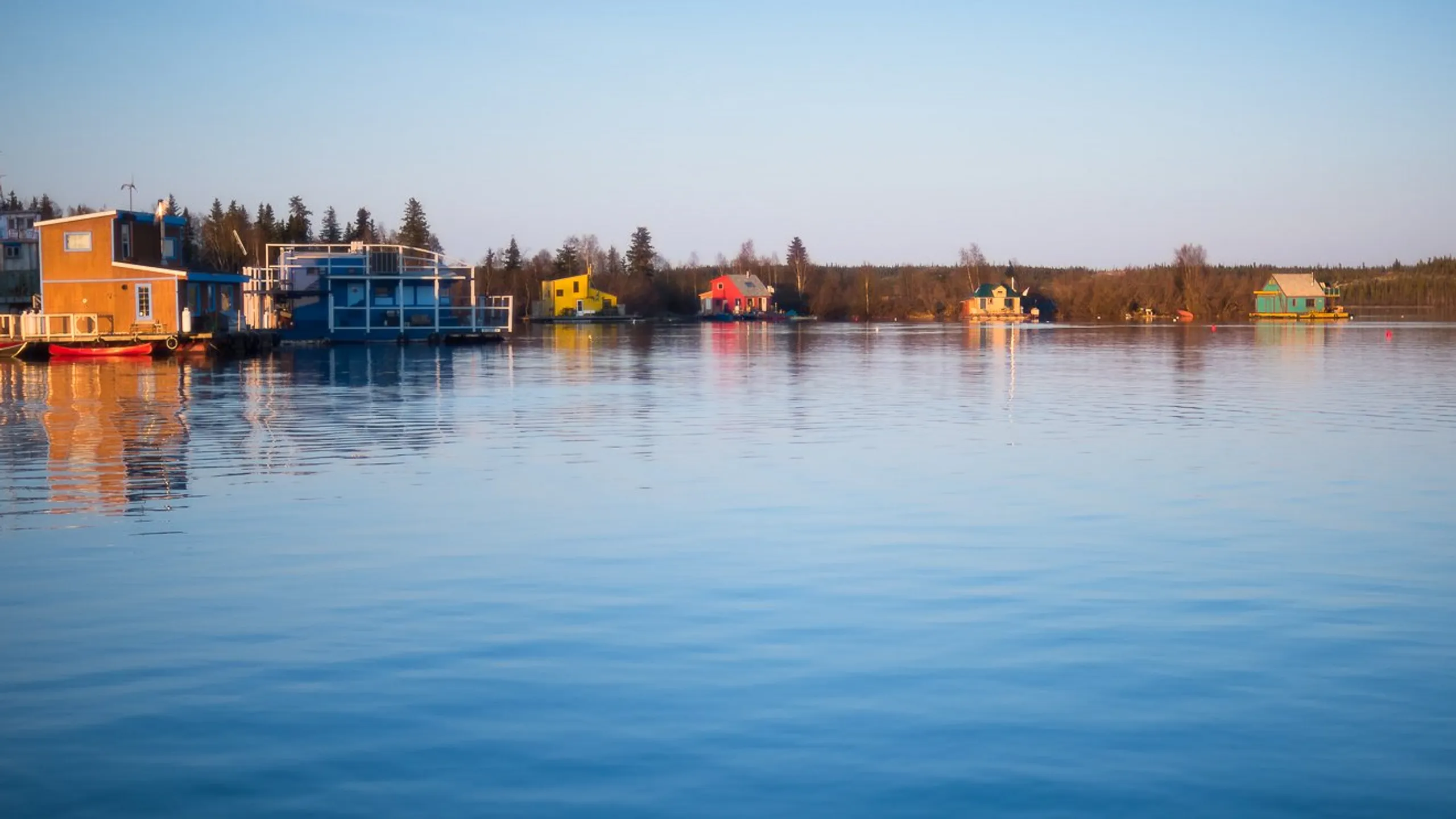 Colourful houseboats on the water in Yellowknife at sunset
